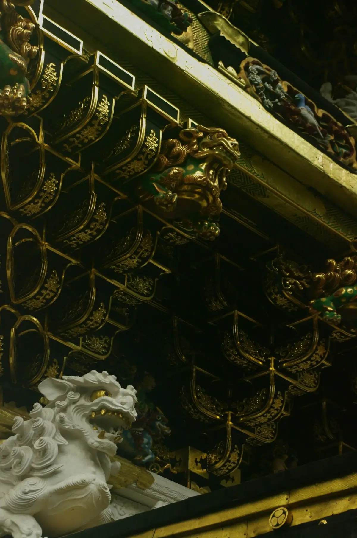 Gold decoration and white animal carvings beneath a roof at Nikko Toshogu Shrine