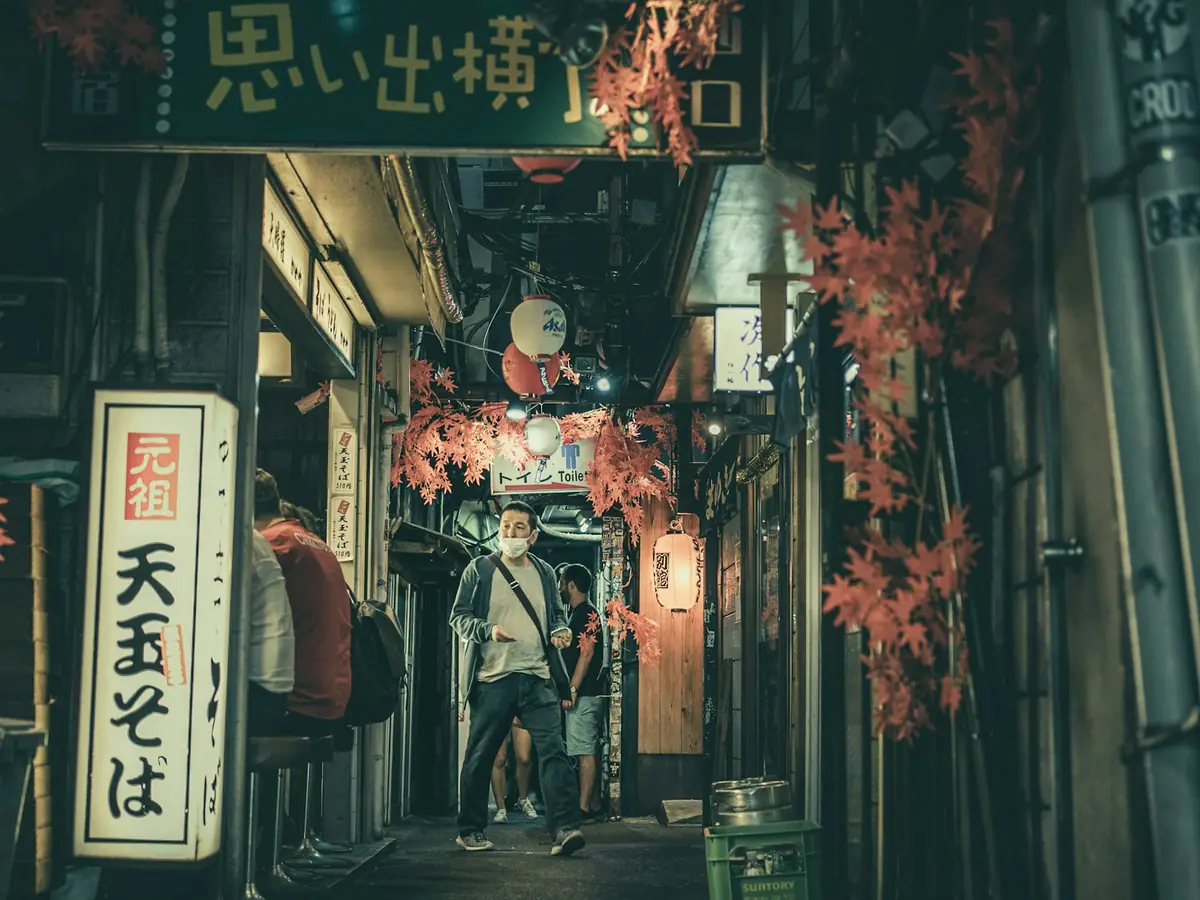 Restauranger längs en smal gränd under en skylt med texten Omoide Yokocho