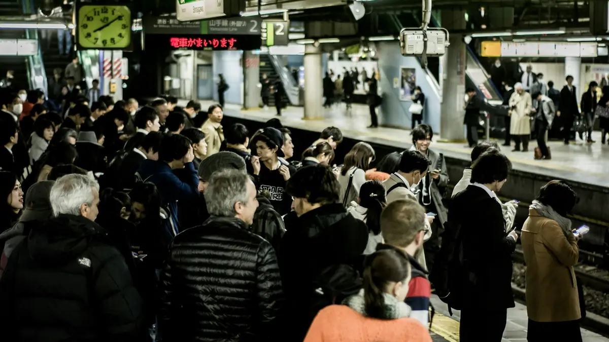 People lined up on a station platform waiting for a train